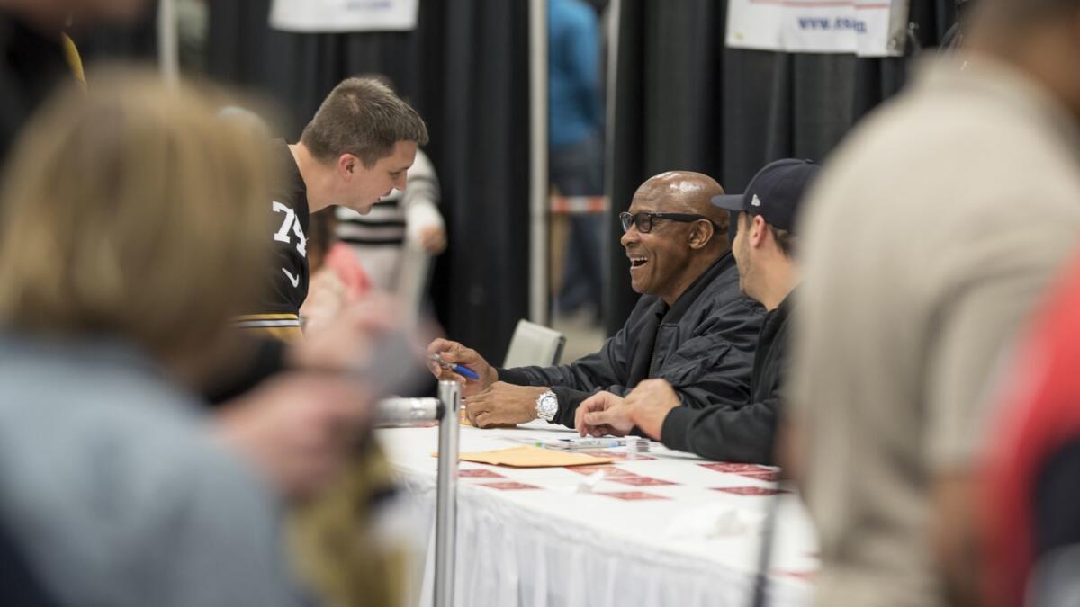 USC athletic director Lynn Swann speaks with a fan while signing autographs at a memorabilia convention in Chantilly, Va., on Saturday.