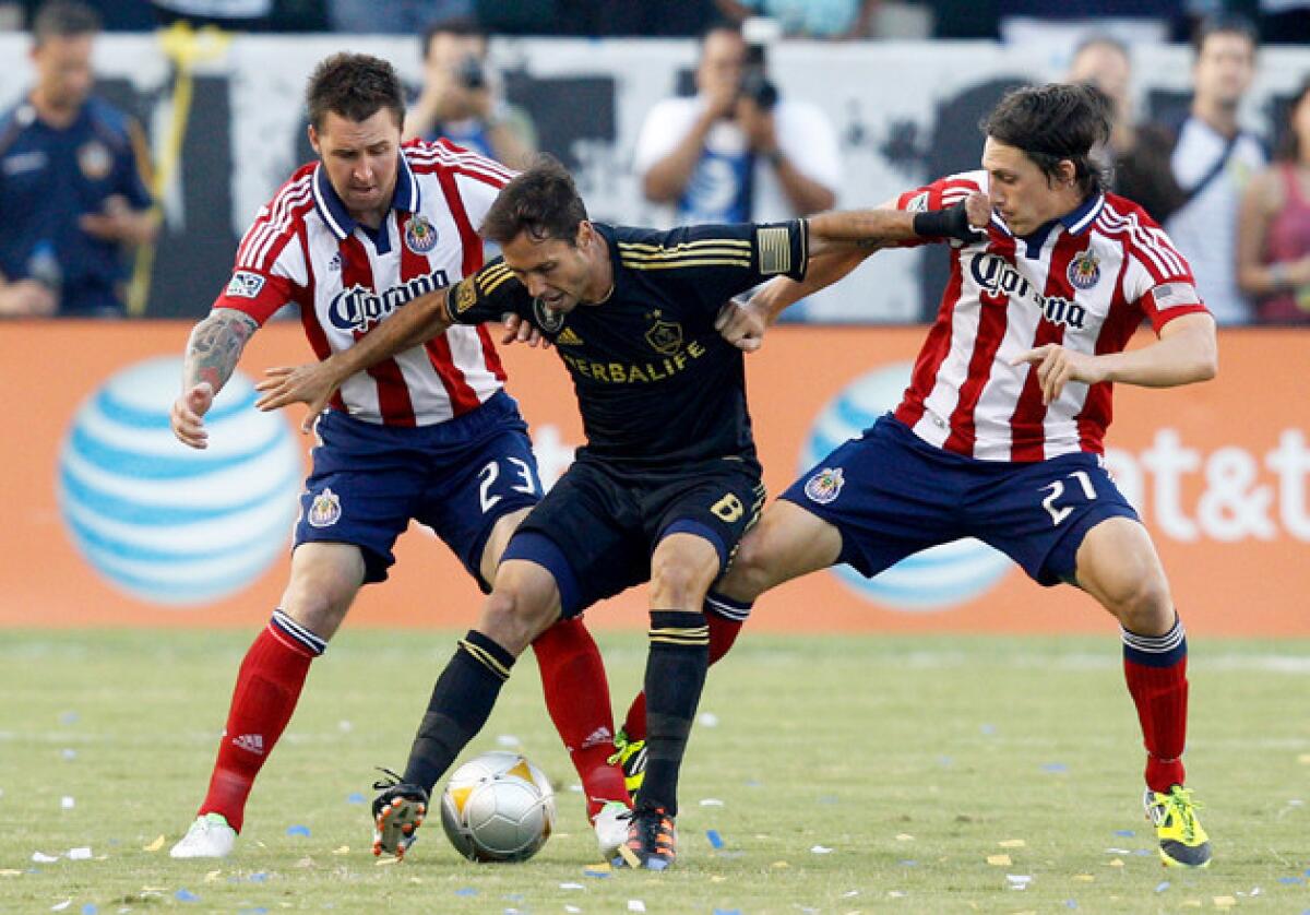 Galaxy's Marcelo Sarvas, center, is guarded by Chivas' Danny Califf, left, and Jose Correa during a match last season.