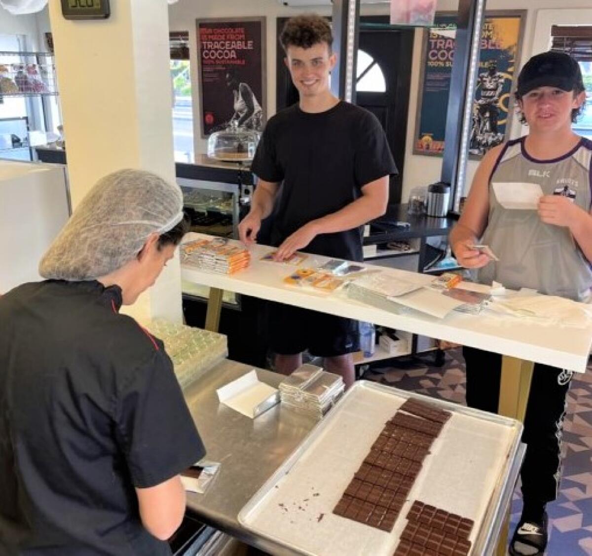 Camille McKenna wraps chocolate in foil while her stepson, Eoin, 25, and son, Gino, 15, add the Ukraine support stickers.
