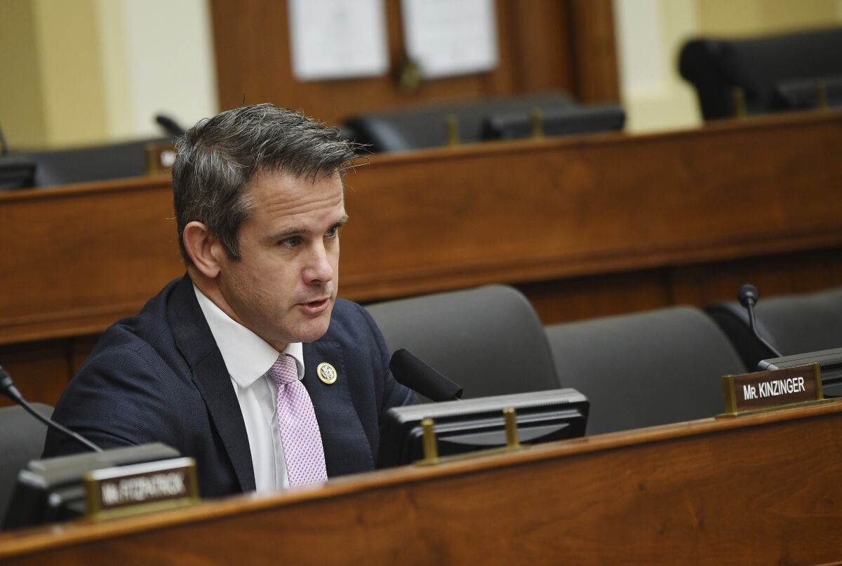 Rep. Adam Kinzinger sits in the House behind his nameplate, speaking into a microphone.