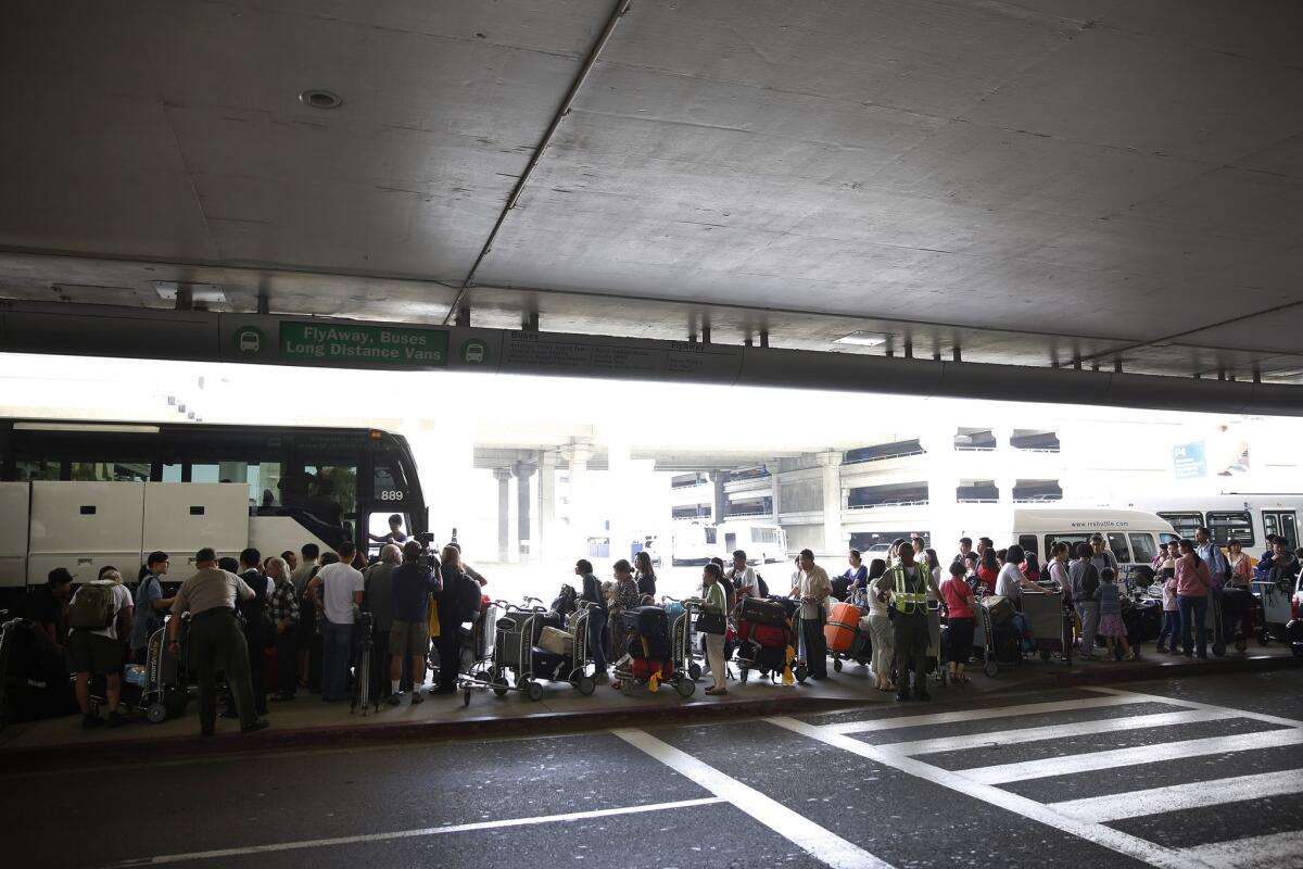 San Francisco-bound passengers who were diverted to Los Angeles after the crash of an Asiana Airlines plane wait at LAX for buses to take them to hotels Saturday.