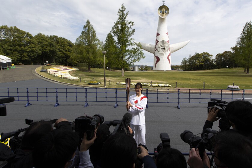 Former Olympian Aya Terakawa, participating as an Olympic torch relay runner, poses for the media before she carries the torch during the first day of the Osaka round at a former Expo site in Suita, north of Osaka, western Japan, Tuesday, April 13, 2021. The Tokyo 2020 Olympic kick-off event which was rescheduled due to the coronavirus outbreak was yet rearranged to hold at the former Expo park, instead of public streets, to close off the audience from the even, following the mayor's decision as Osaka has had sharp increases in daily cases since early March. (AP Photo/Hiro Komae)