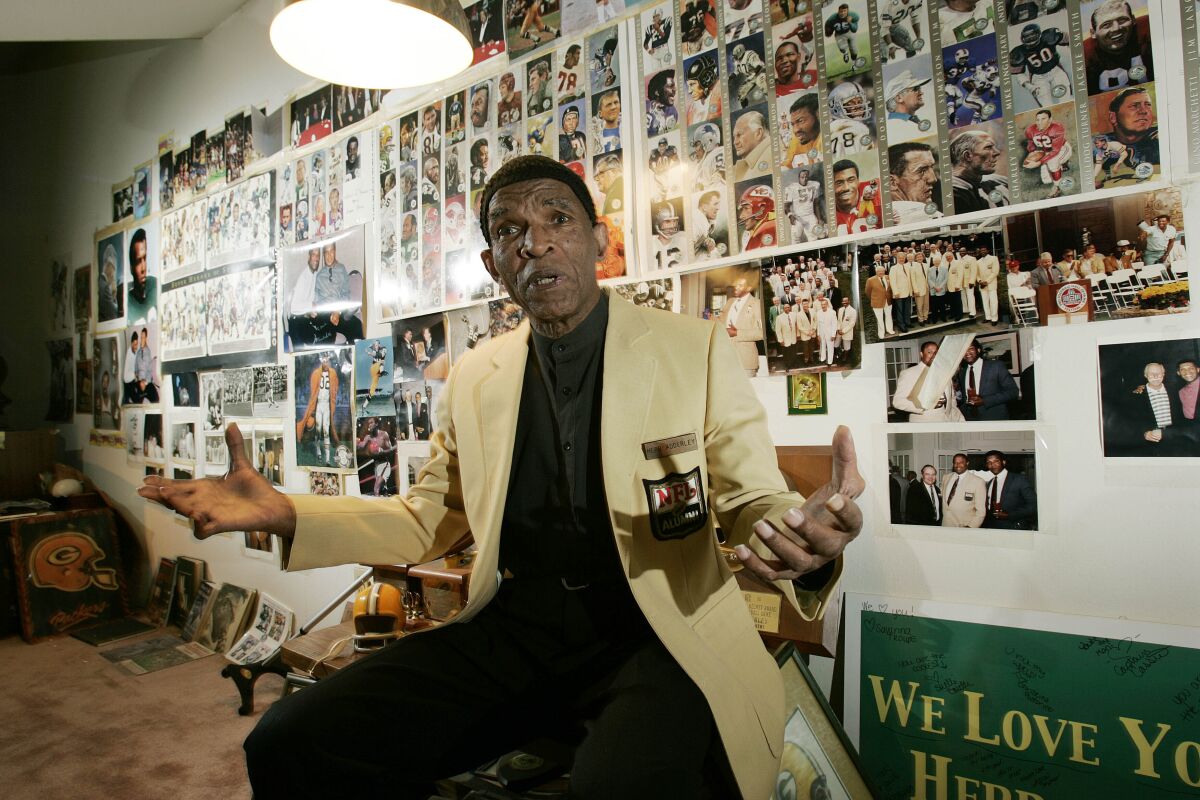 Hall of Fame cornerback Herb Adderley speaks as he sits in a room full of memorabilia.