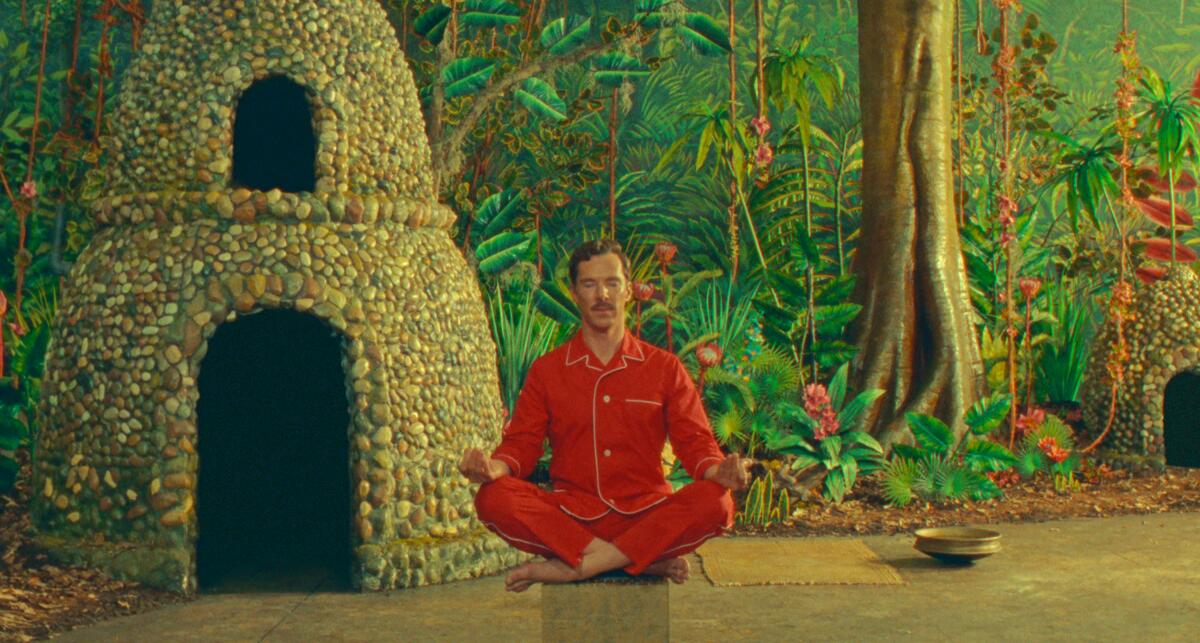 A man is sitting cross-legged in his pajamas in the middle of a jungle scene in "The wonderful story of Henry Sugar."