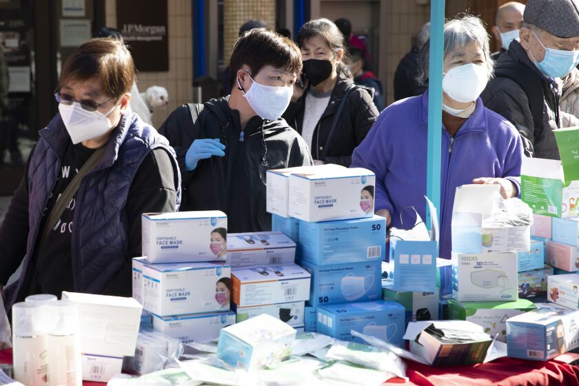 Customers shop for disposable face masks at the Chinese New Year Flower Market Fair in Chinatown in San Francisco