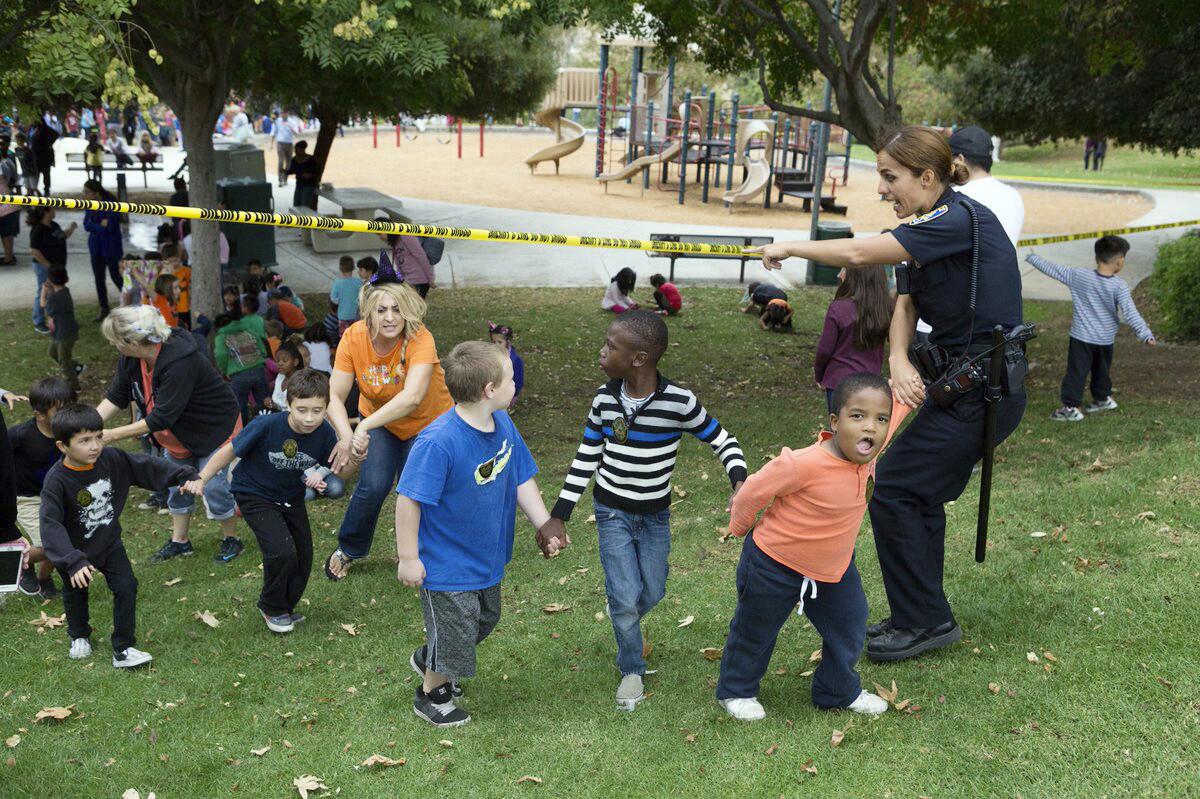 La policía ayuda a salir a niños de una escuela mientras esperan a sus padres luego de que un padre se atrincheró en un aula de la escuela primaria Castle View en Riverside, California.