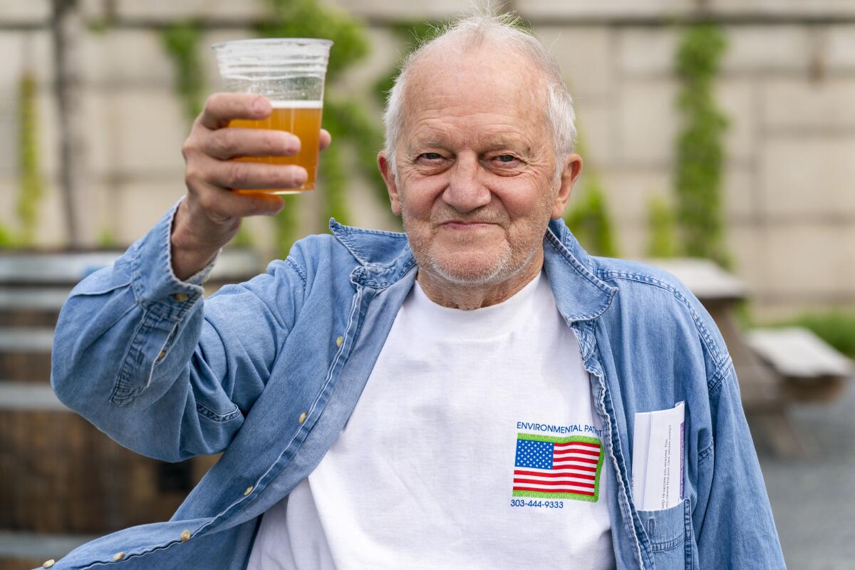 A smiling man raises a glass of beer