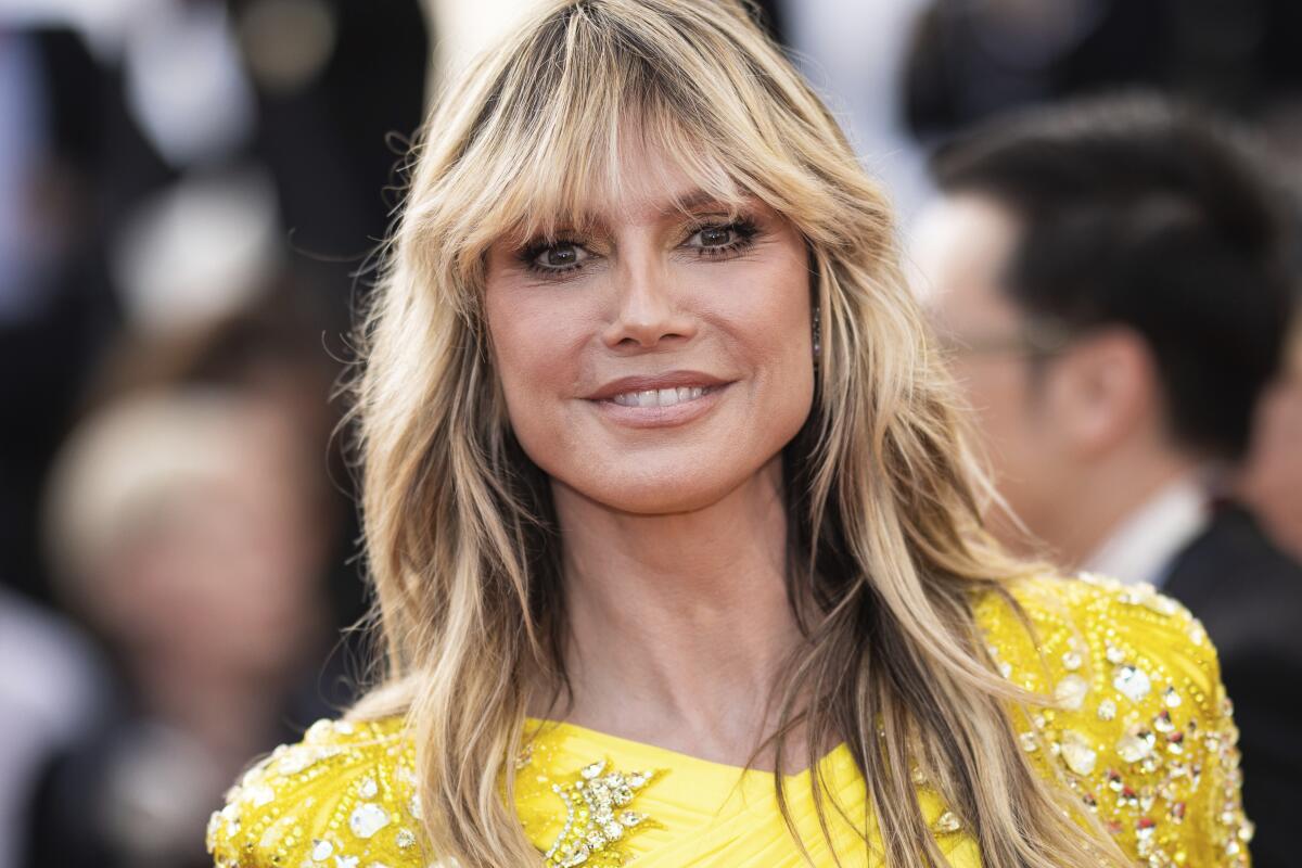 Heidi Klum smiles in a bedazzled yellow gown and blond bangs