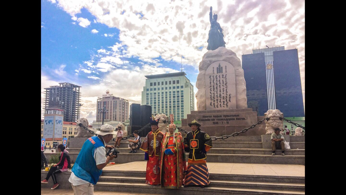 Mongolians rent traditional costumes and pose in front of the main monument in Ulan Bator's central square, which depicts Damdiny Sukhbaatar (1893-1923), a key leader of the 1921 revolution. The inscription reads, in classical Mongolian: "Our nation, once in unity joined, our strengths combined and in resolve forward stepped, shall see no destination unreachable, no things unknown or unattainable, and will reach the pinnacle of happiness, which is only up to our own resolute will."