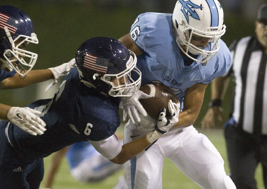 Newport Harbor High's Nate Harding (6) attempts to strip the ball as he forces Corona del Mar's Reece Perez out of bounds.