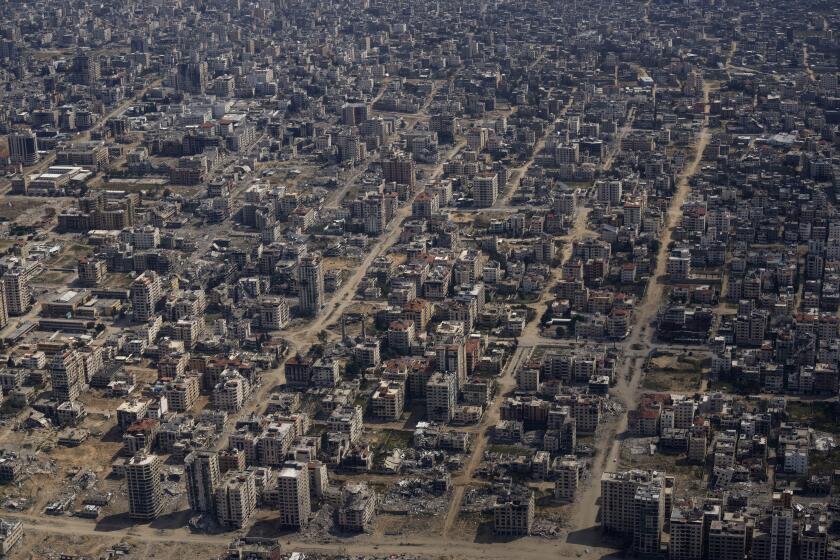 Destroyed buildings are seen through the window of an airplane from the U.S. Air Force overflying the Gaza Strip, Thursday, March 14, 2024. (AP Photo/Leo Correa)