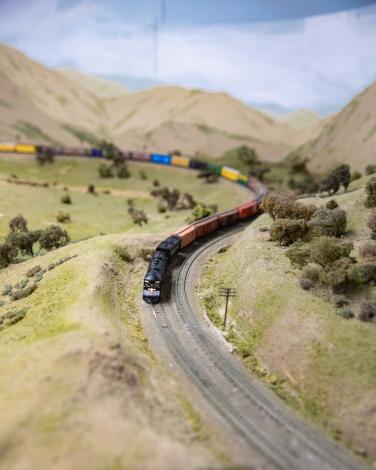 A miniature train runs on a track amid fake grassy hills.