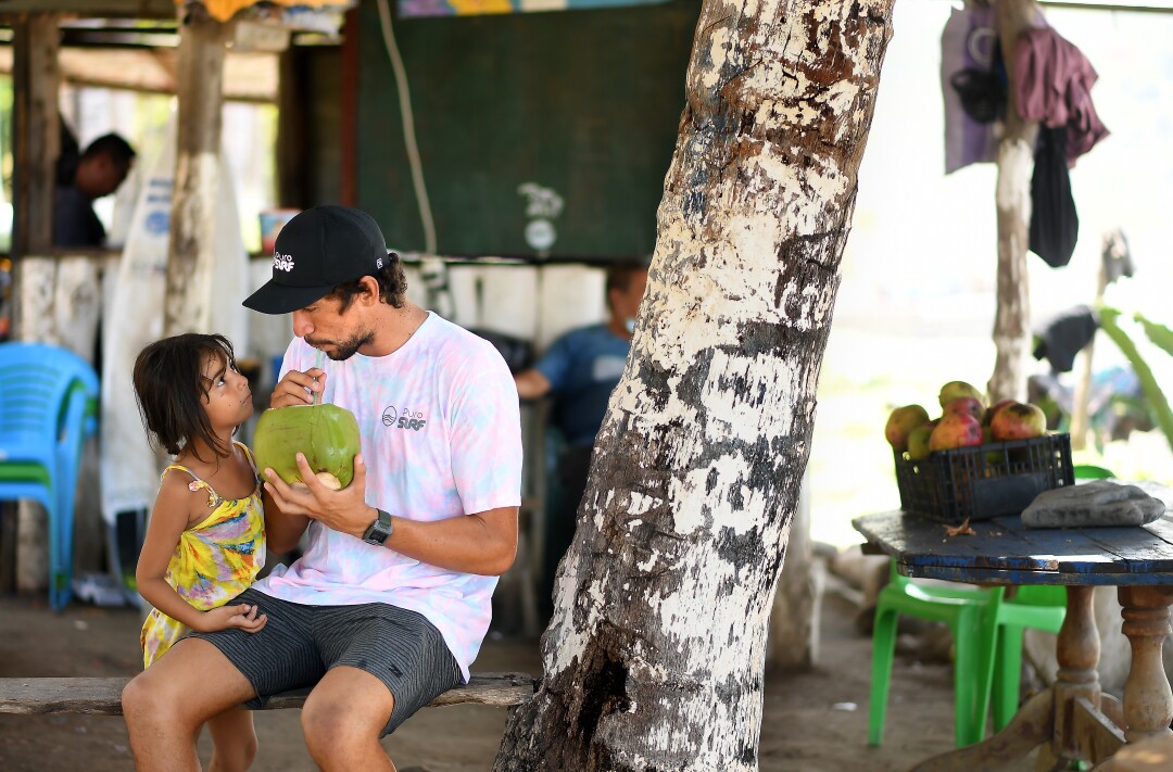  Bryan Perez sips on a coconut with family at his father's refreshment stand