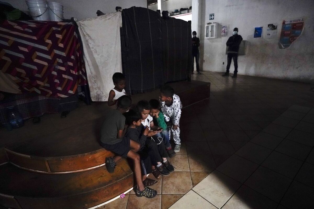 Children gather around a phone in a migrant shelter.
