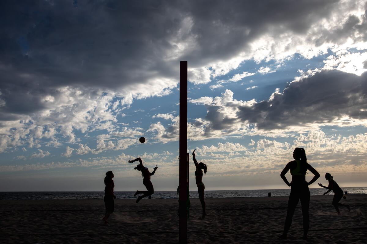 Scattered clouds serve as a backdrop to a beach volleyball game in Hermosa Beach. 