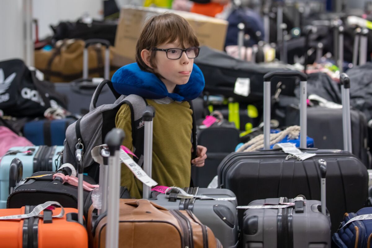 A 9-year-old child searches for his luggage among the sea of bags at an LAX baggage claim area