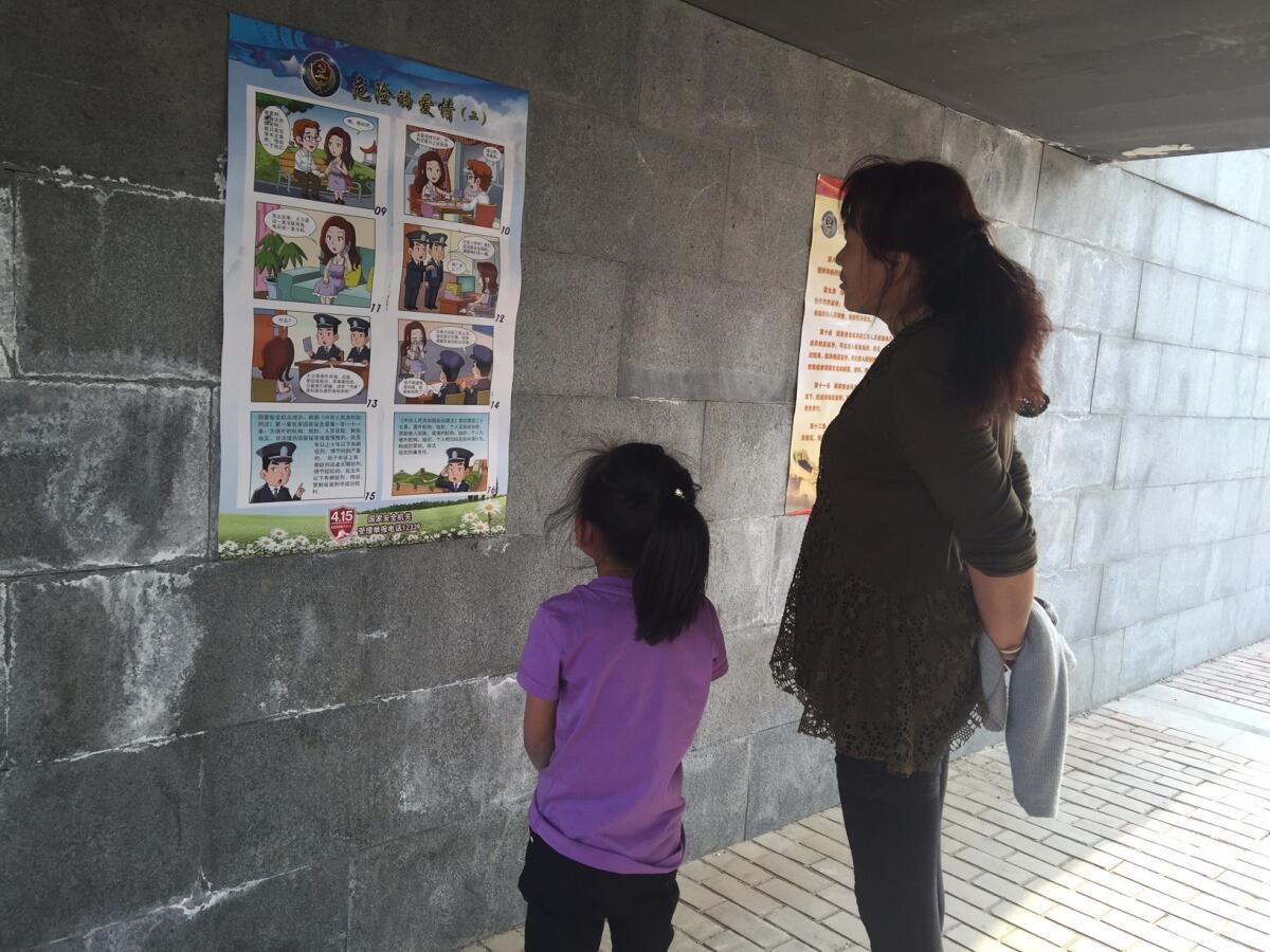 A woman and her daughter look at a "Dangerous Love" cartoon in Beijing that warns women not to date foreign men.