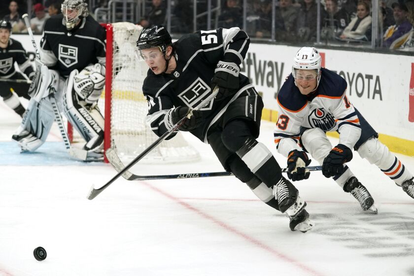 Los Angeles Kings defenseman Troy Stecher, left, moves the puck while being followed by Edmonton Oilers right wing Jesse Puljujarvi during the third period of an NHL hockey game Thursday, April 7, 2022, in Los Angeles. (AP Photo/Mark J. Terrill)