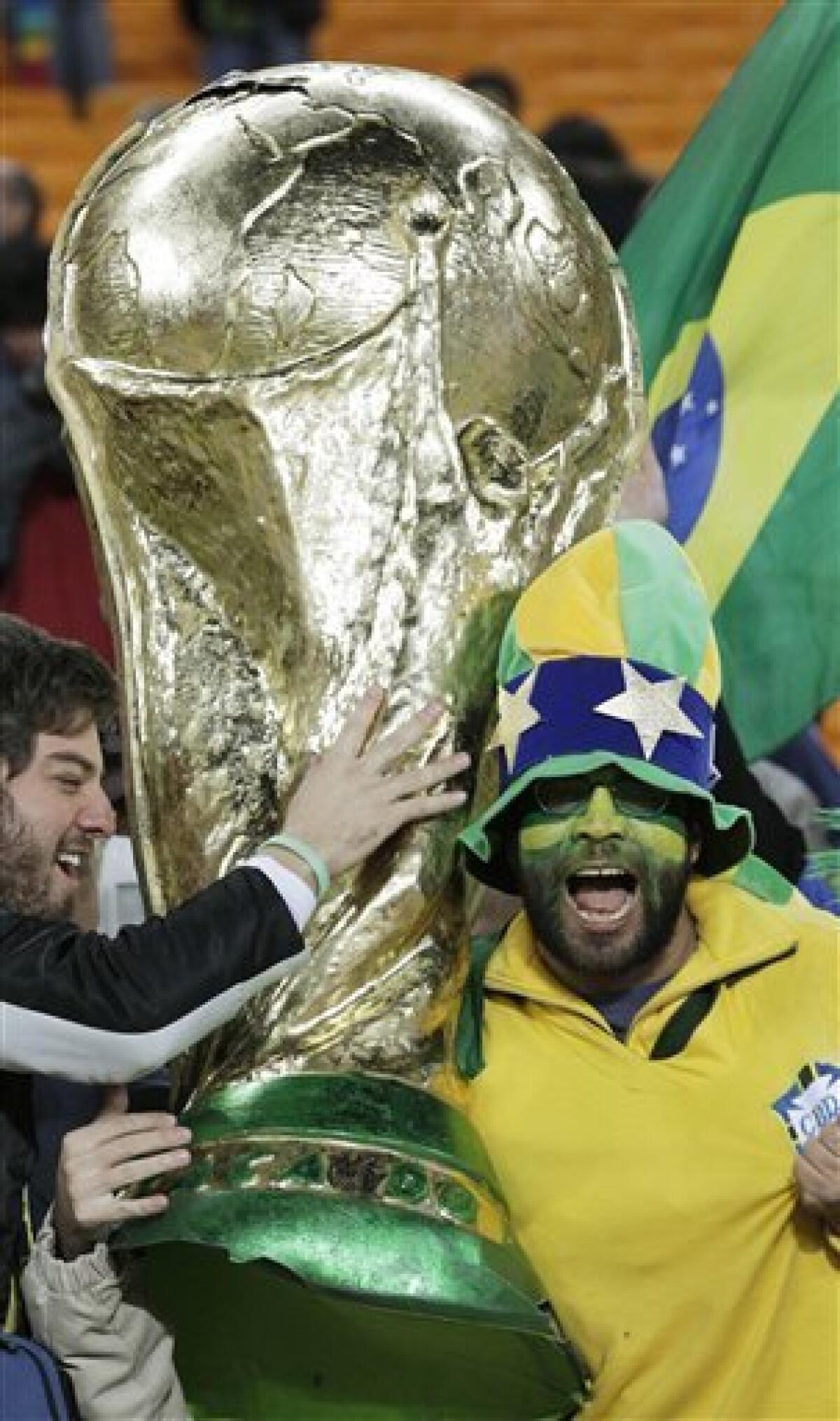 Brazil fans celebrate with a giant mock World Cup trophy after the World Cup group G soccer match between Brazil and Ivory Coast at Soccer City in Johannesburg, South Africa, Sunday, June 20, 2010. Brazil won 3-1. (AP Photo/Frank Augstein)
