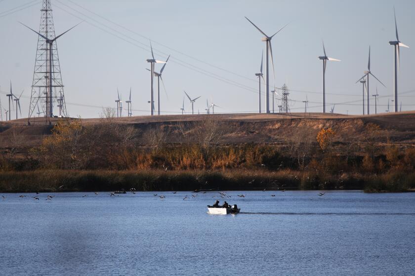 RIO VISTA, CA - NOVEMBER 29: Wind turbines and boaters along the Sacramento River taken from Sherman Island along State Route 160 on Tuesday, Nov. 29, 2022 in Rio Vista, CA. Scenes along the Sacramento Delta. (Gary Coronado / Los Angeles Times)
