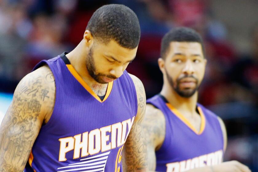 Brothers Marcus, left, and Markieff Morris of the Phoenix Suns walk onto the court before a game against the Houston Rockets on March 21.