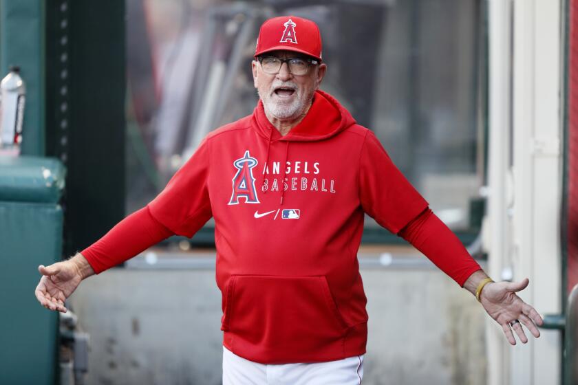 Los Angeles Angels' manager Joe Maddon looks for players on his team in the dugout.