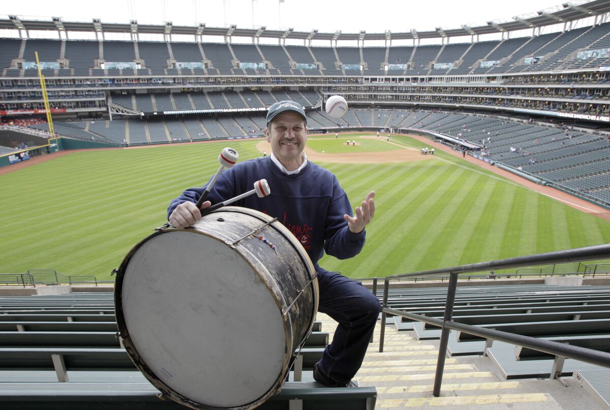 FILE - In this April 27, 2011, file photo, Cleveland Indians fan John Adams poses in his usual centerfield bleacher seat with his ever-present bass drum before a baseball game between the Indians and the Kansas City Royals in Cleveland. Adams, who pounded a drum while sitting in Cleveland's outfield bleachers during baseball games for five decades, has died. He was 71. The Guardians announced his passing on Monday, Jan. 30, 2023. (AP Photo/Amy Sancetta, File)