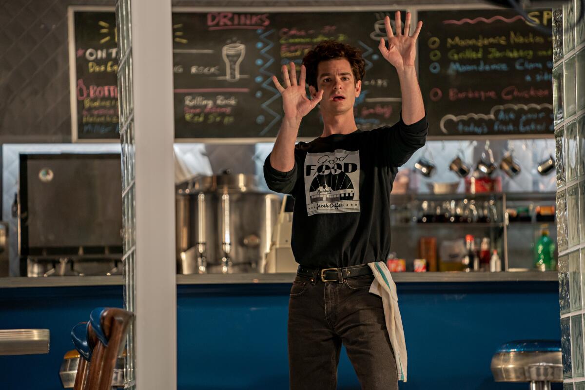 A young man in a cafe holds up his hands in the movie "Tick, Tick ... Boom!"