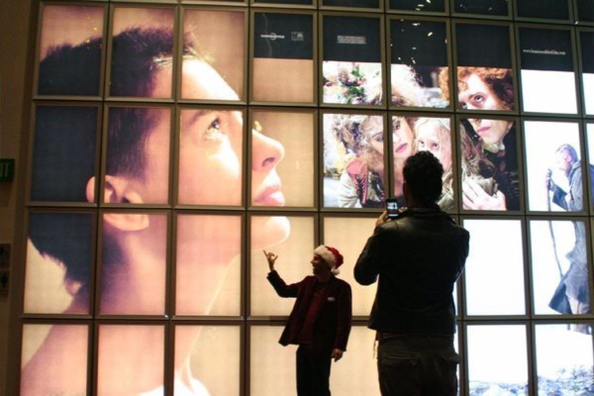 Fans in front of a promotional sign for "Les Miserables," which depicts Anne Hathaway playing "Fantine." The film adaptation of the stage classic premiered on Christmas Eve at the ArcLight.