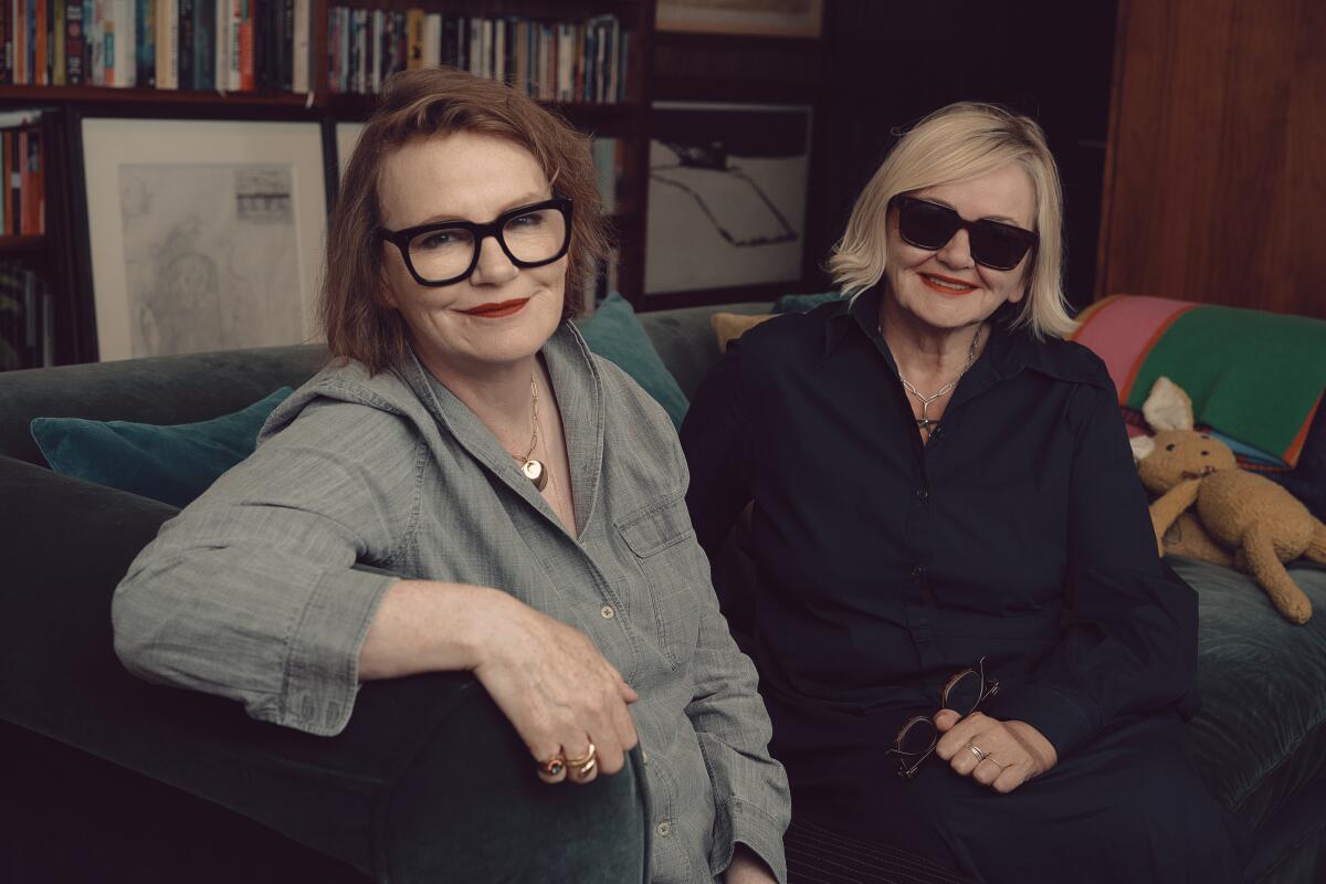 Two women sit on a sofa for a portrait.