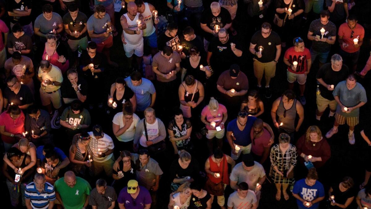 Mourners on June 13, 2016, observe a moment of silence for the Pulse nightclub shooting victims during a vigil outside the Dr. Phillips Center for the Performing Arts in Orlando, Fla.