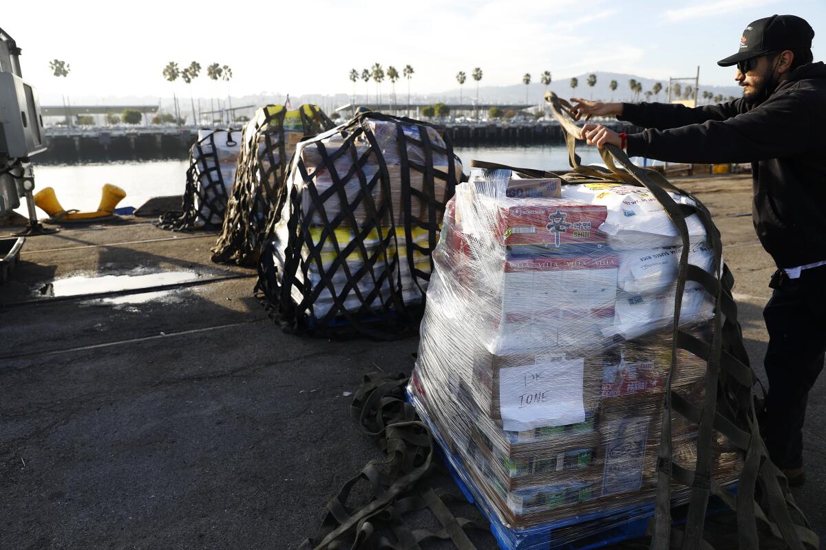 A worker handles a pallet of goods on a shipping dock.