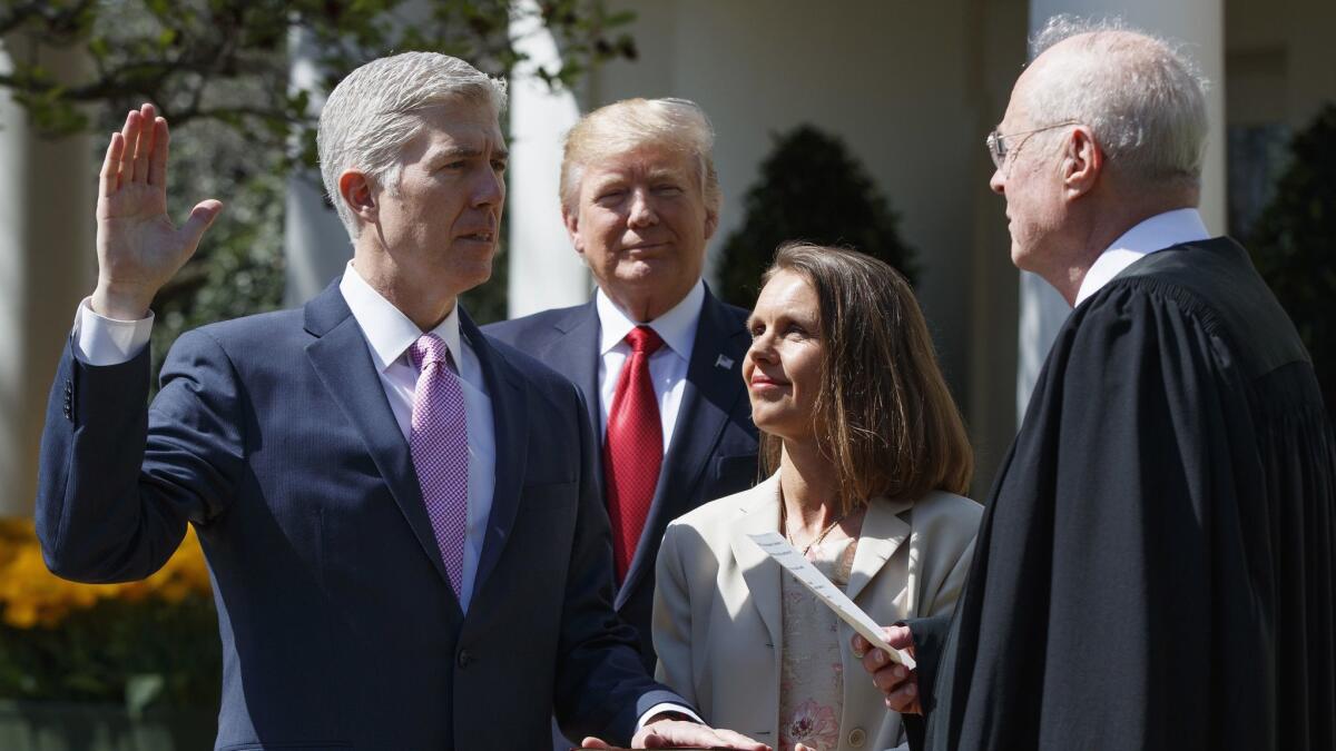 Supreme Court Justice Anthony M. Kennedy, right, administers the judicial oath to Justice Neil M. Gorsuch, who was accompanied by his wife, Marie Louise, at the White House in 2017.