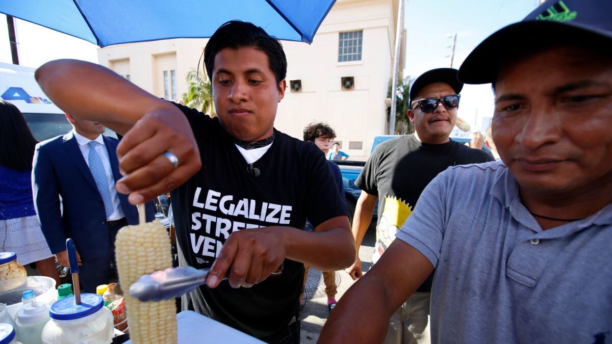 Benjamin Ramirez, left, with his father, Alex Ramirez, right, serving food from their cart during a rally in Hollywood.