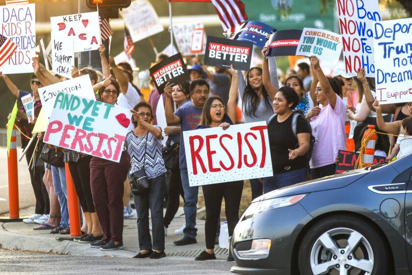 People protest President Trump's decision to end the DACA program while on Via Rancho Parkway in front the Westfield North County shopping mall.