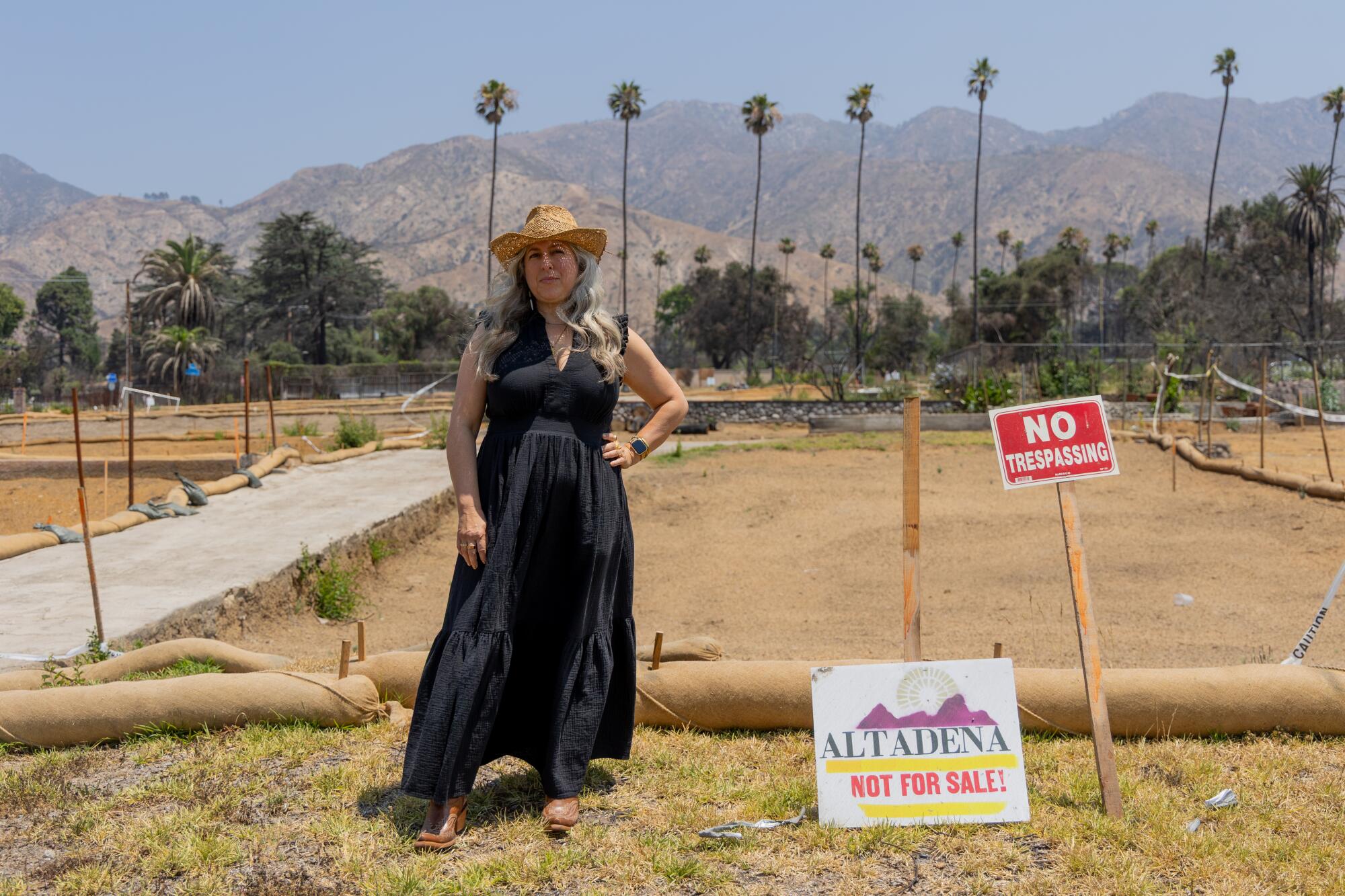 A woman stands in an empty lot.