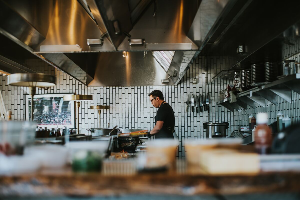   An employee works alone in Underbelly restaurant in North Park in this photo from Lindsay Kreighbaum's photo essay on restaurants operating during the COVID-19 pandemic.