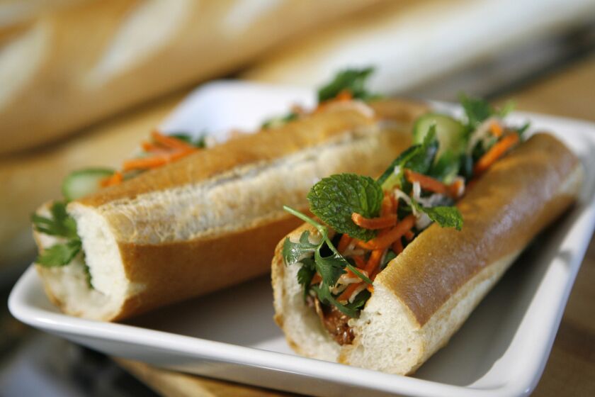 Two halves of a bahn mi on a white ceramic plate.