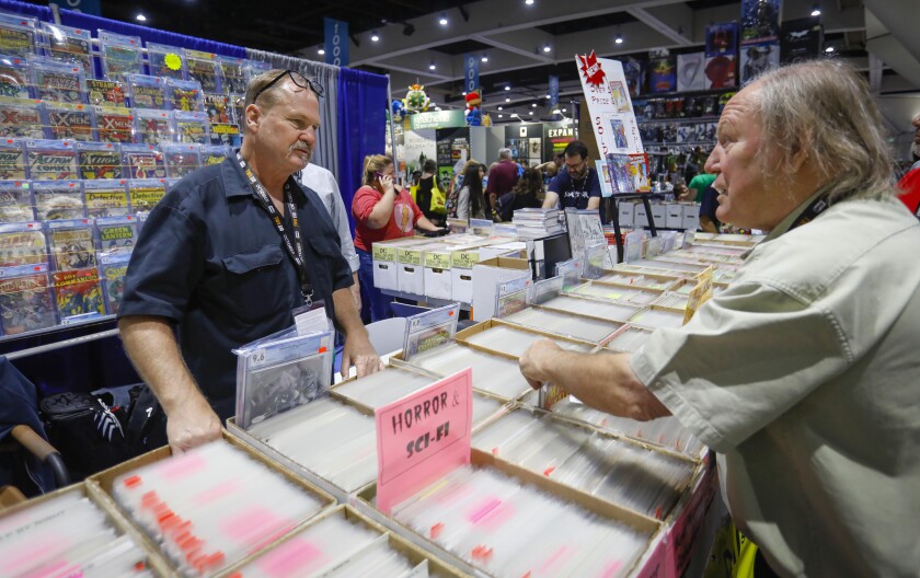 Jamie Newbold, left, overseeing his Southern California Comics' booth at Comic-Con, talks to Michael Tacchia, a collector from San Bernardino.
