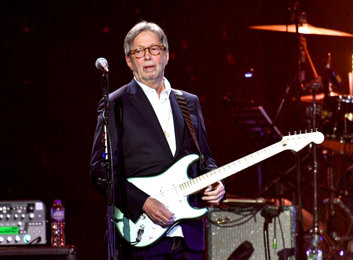 An older man plays a guitar onstage.