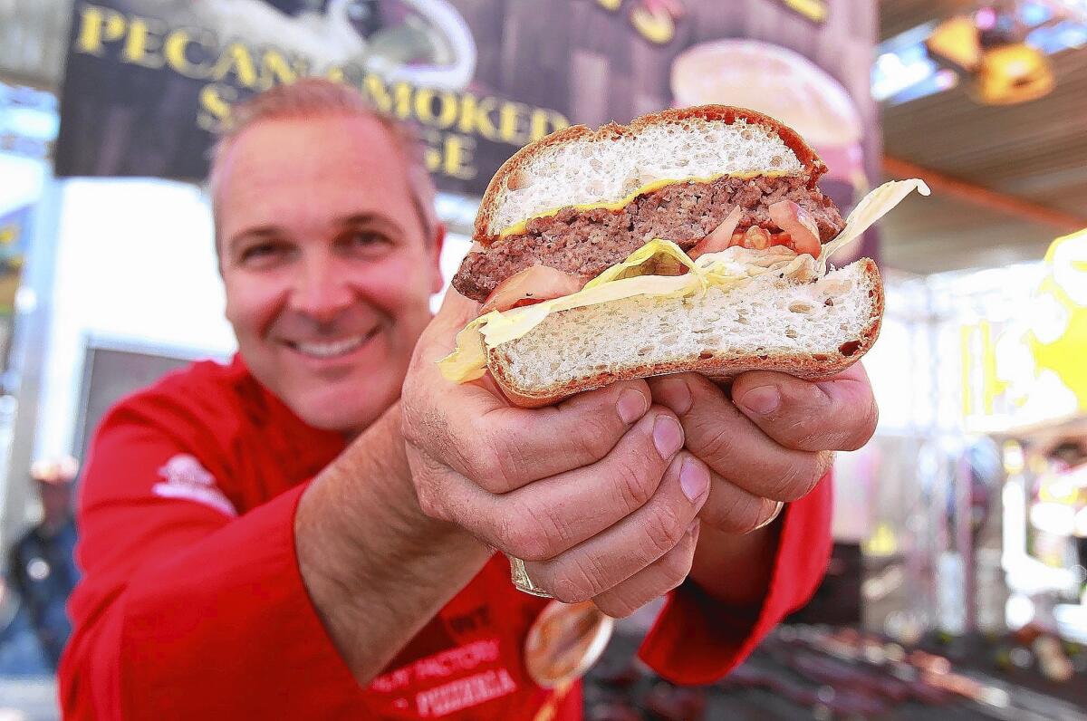 Dominic Palmieri shows off a Biggy's Meat Market cheeseburger made with gluten free bread at the Orange County Fair.