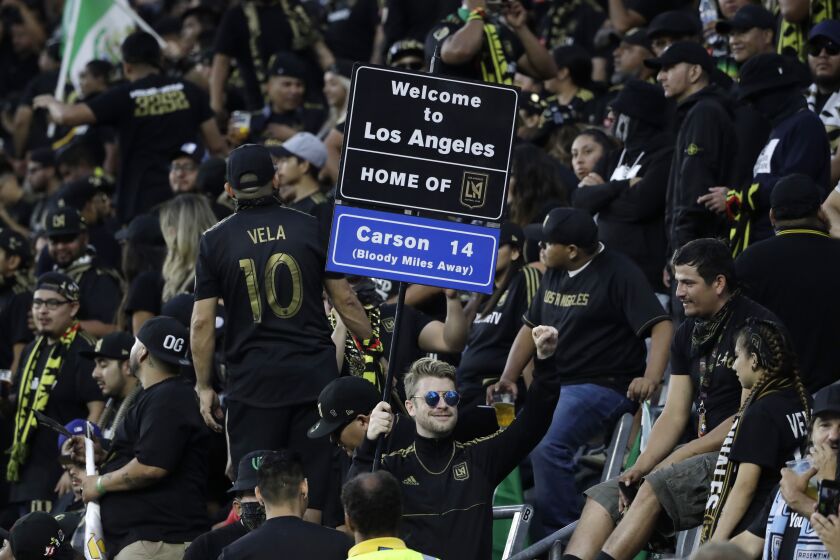 A fan holds a sign during the first half of an MLS soccer match between Los Angeles FC and Los Angeles Galaxy, Sunday, Aug. 25, 2019, in Los Angeles. (AP Photo/Marcio Jose Sanchez)