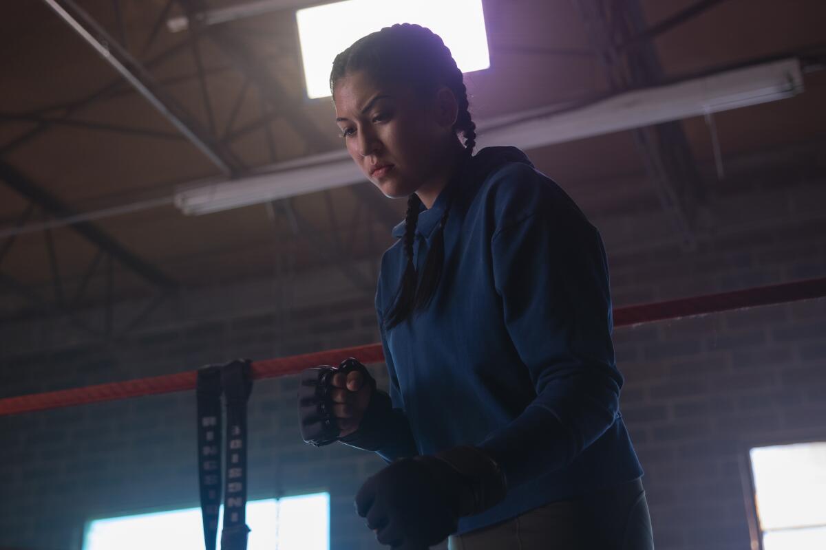 A woman wearing sparring gloves in a fighting pose