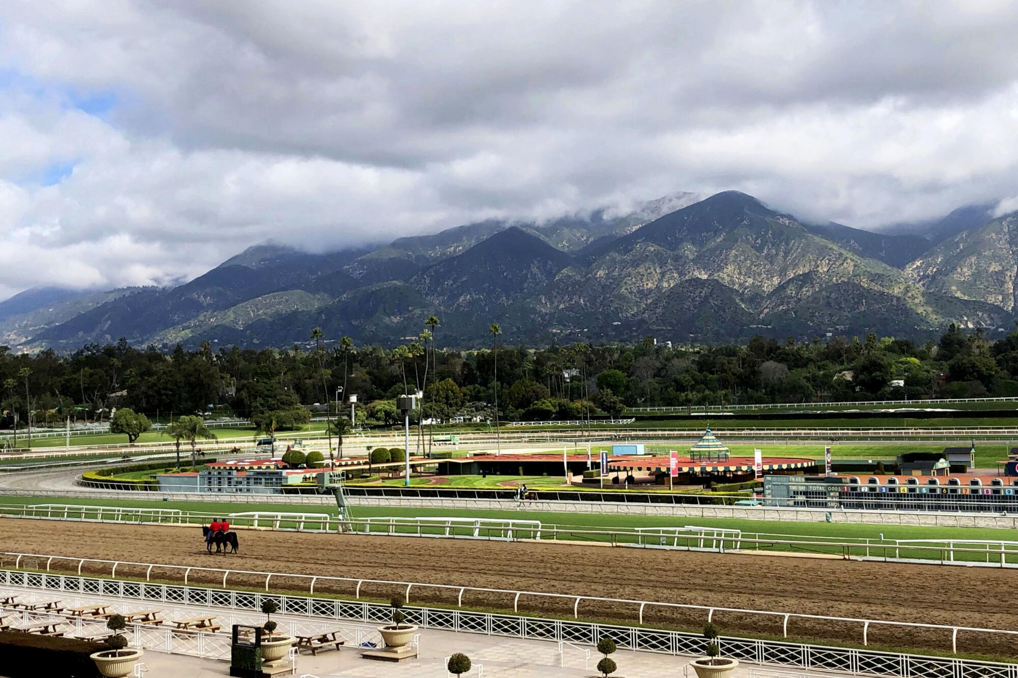Horses and riders are on the track at Santa Anita Park in Arcadia.