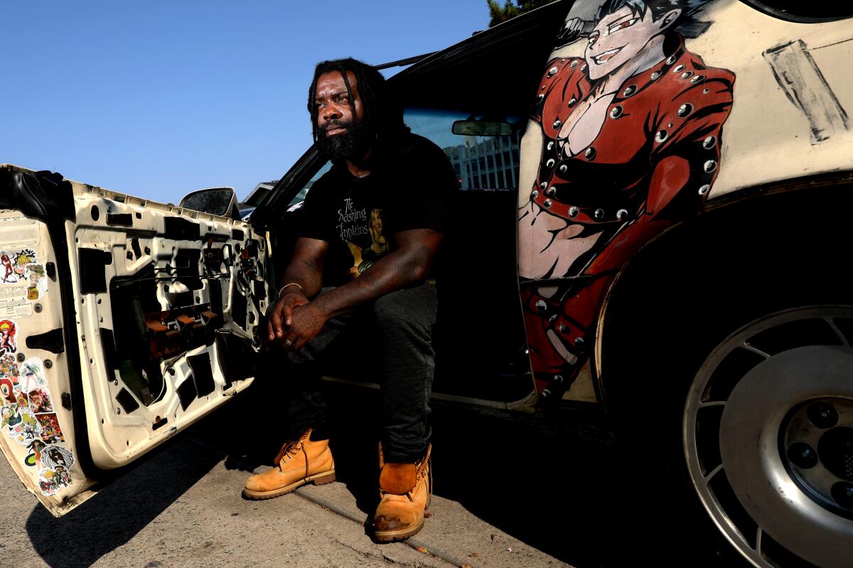 Bryant Mangum sits in his car, with the car door open wide