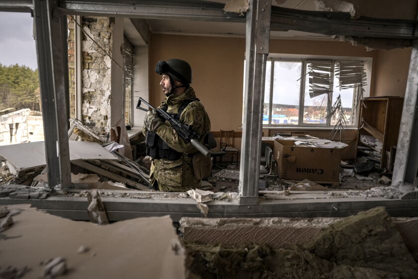 A Ukrainian serviceman stands in a heavily damaged building in Stoyanka, Ukraine
