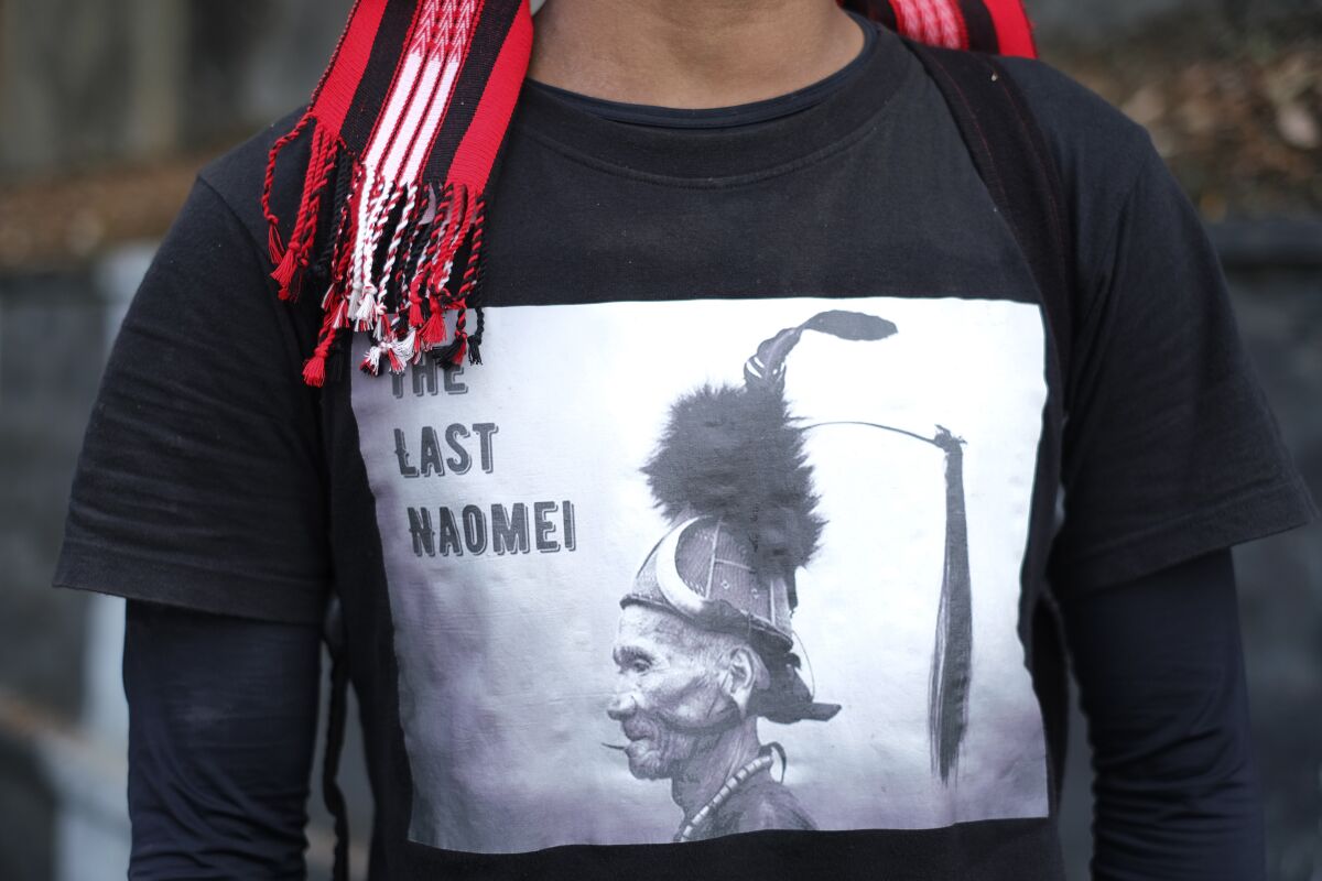 Manpong Konyak, 23, from Oting village, wears a traditional scarf and a t-shirt showing a portrait of his tribesman that reads "the last warrior" during a gathering at the end of a 70-kilometer (43 miles) walk demanding the repeal of the Armed Forces Special Powers Act (AFSPA) in Kohima, in the northeastern Indian state of Nagaland, Tuesday, Jan. 11, 2022. "We want peace. We do not want violence. AFSPA must be repealed because we are a peace-loving people," Manpong said. Fourteen civilians were killed by the Indian army in December, twelve of them from Oting village. (AP Photo/Yirmiyan Arthur)