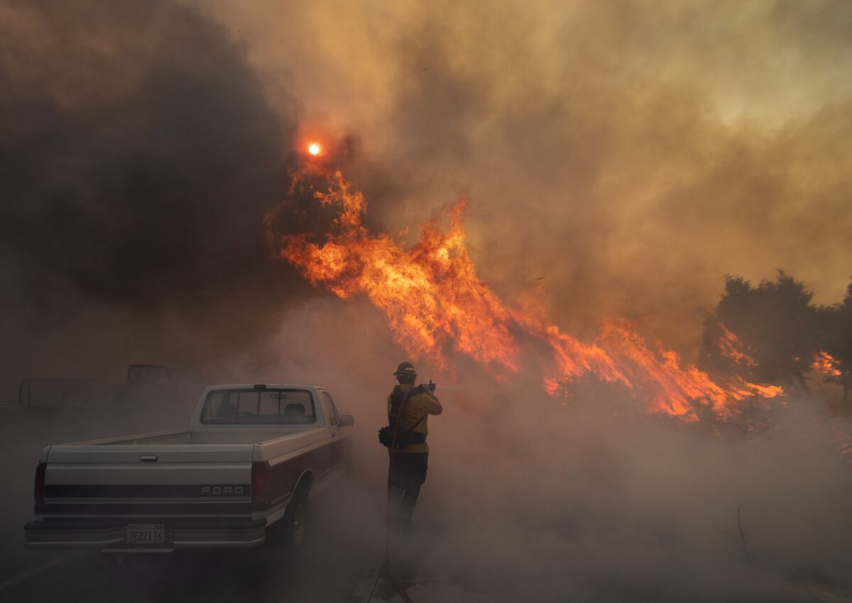 Firefighter Raymond Vasquez braves tall flames as he fights the advancing Silverado fire fueled by Santa Ana winds.