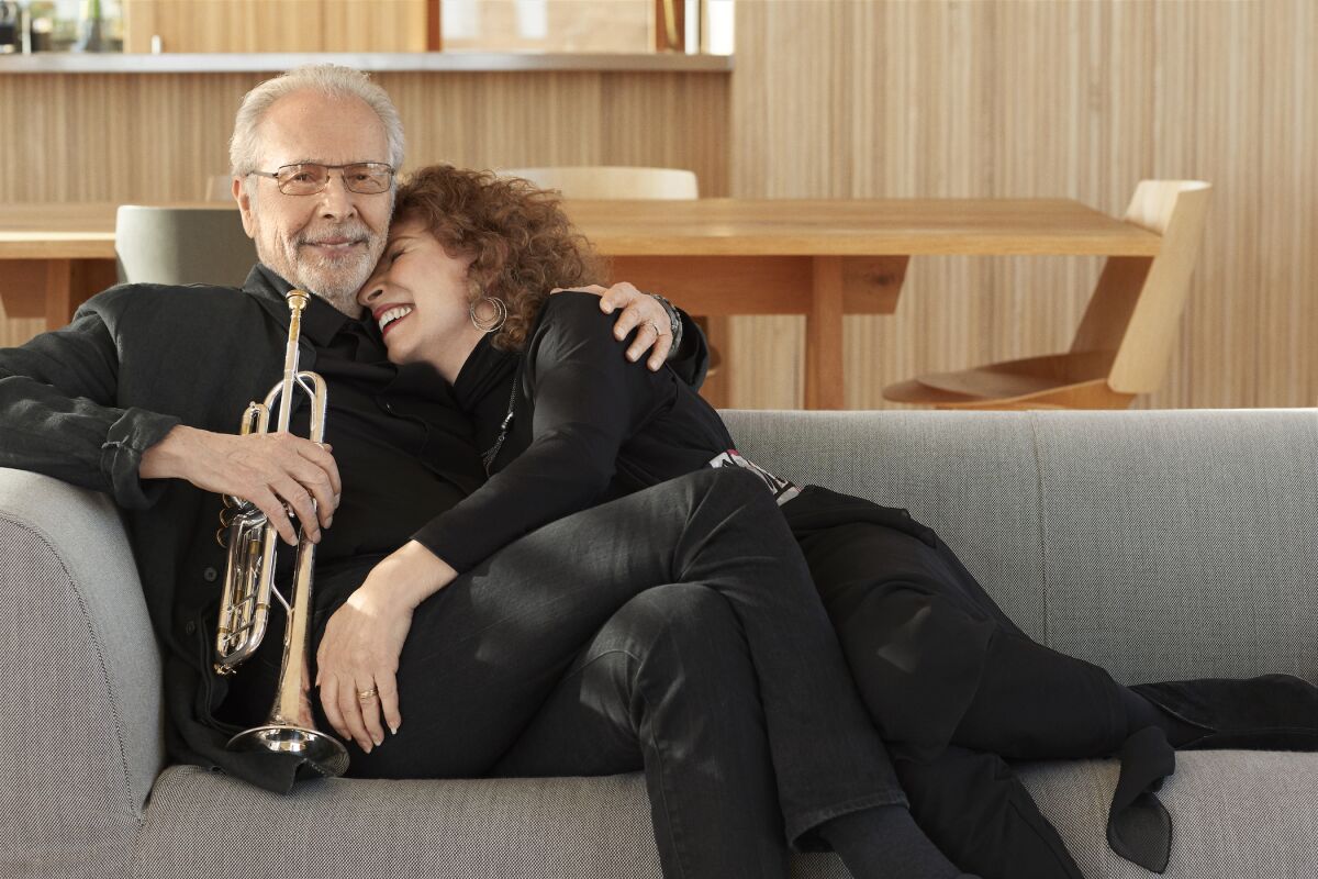 Trumpet player Herb Alpert and singer Lani Hall snuggle on the coach
