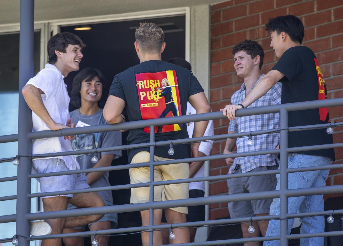 A group of young men talk on a balcony
